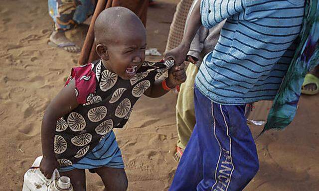A child cries out as his brother pulls him after they were handed food at a World Food Programme, WFP