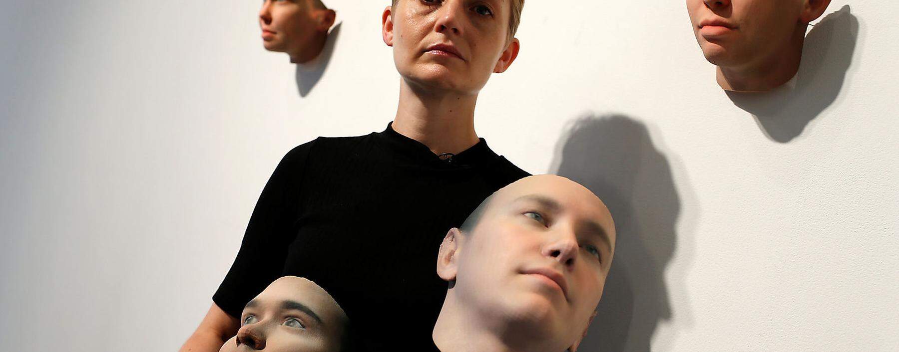 Artist Heather Dewey-Hagborg poses with various 3-D printed masks at the Fridman gallery in New York City