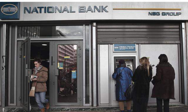 People make transactions at an ATM outside a National Bank of Greece branch in Athens
