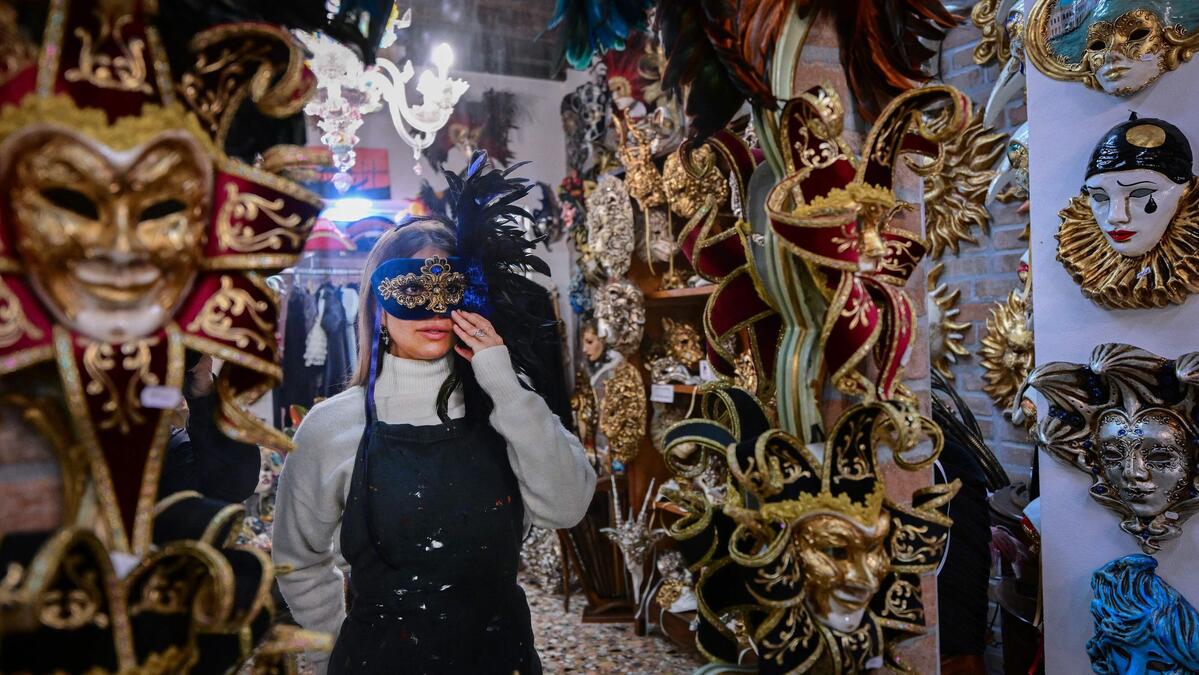 TOPSHOT - An employee tries on a mask at La Bauta Mask and Carnival Laboratory and workshop on the first day of Venice carnival, on February 14, 2025. The carnival will run till March 4, 2025. This year, the theme of one of the most famous carnival in the world is Casanova, as the 'Serenissima' celebrates the 300th anniversary of the famous man's birth. Tourists have started to arrive, and many of them prepare for the big event as the opening day falls on Valentine's Day, decorating their masks, and trying their costumes on. (Photo by Tiziana FABI / AFP)