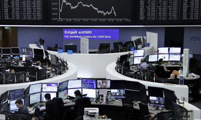 Traders work at their desks in front of the German share price index DAX board in Frankfurt