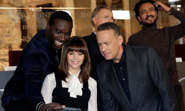 Actor Omar Sy takes a picture with actors Felicity Jones and Tom Hanks looks during a screening of their film ´Inferno´ in Florence