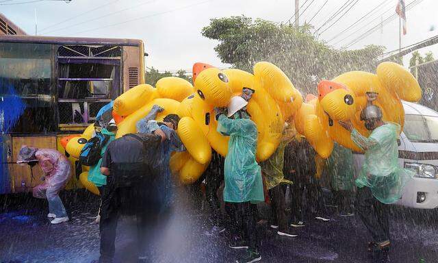 Die Regierungsgegner wehrten sich mit aufblasbaren Schwimmutensilien gegen die Wasserwerfer der Polizei in Bangkok.