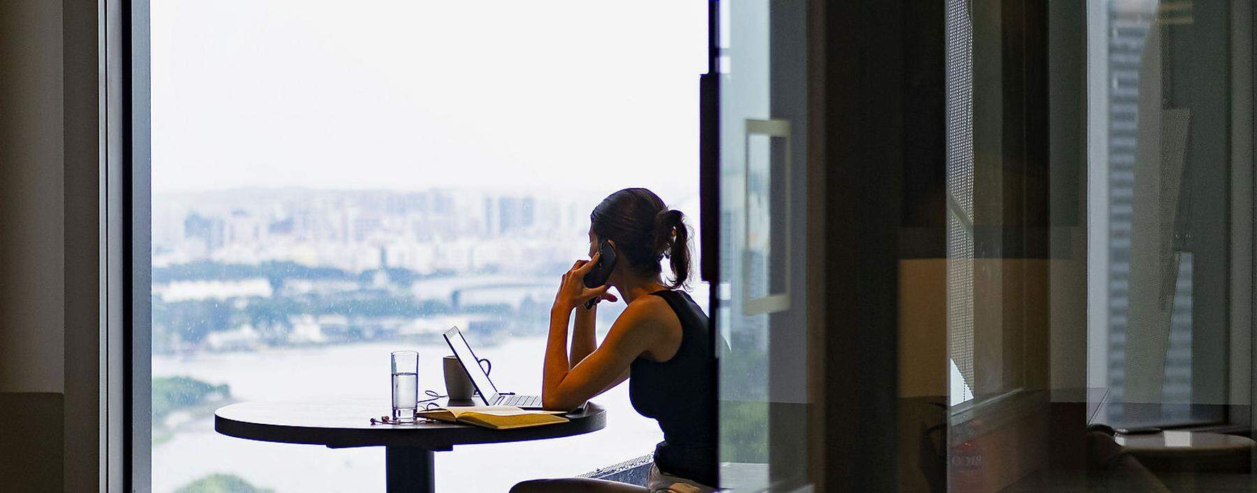 A woman answers a call while looking out the window in co-working space The Great Room´s Centennial Tower location in Singapore