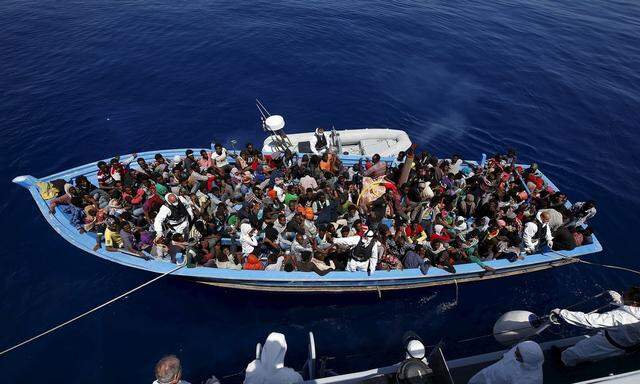 A group of 300 sub-Saharan Africans sit in board a boat during a rescue operation by the Italian Finance Police vessel Di Bartolo off the coast of Sicily