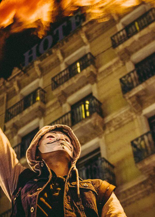 Mit Guy-Fawkes-Maske im Gesicht und Fackel in der Hand: Auch in Katalonien geht es bei den Protesten gegen die Corona-Maßnahmen heiß her. 