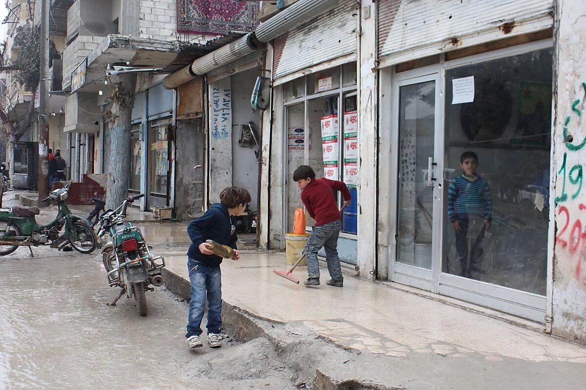 Kinder säubern den Gehsteig vor einem Geschäft. 400.000 Menschen lebten vor dem IS-Angriff in Kobane und Umgebung. Der Großteil der Zivilisten floh während der Gefechte in die Türkei. Mittlerweile sind 200.000 Menschen zurückgekehrt.