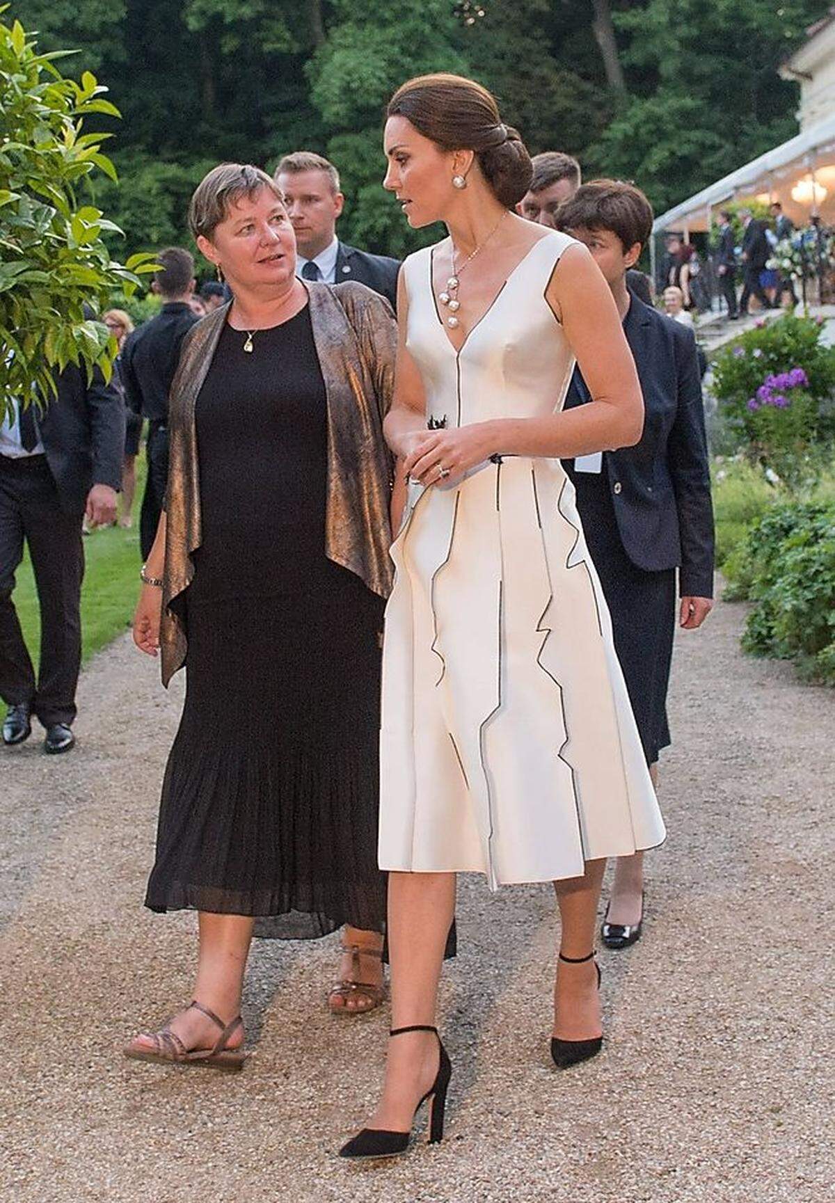 Zu einem Abendtermin in Warschau erschien Kate in einem Cocktailkleid der polnischen Designerin Gosia Baczynska - und es beigeisterte. Die Paneele des Rocks sorgen für einen interessanten 3D-Effekt. Die schwarzen Details des Kleids unterstrich die Herzogin mit schwarzen Pumps mit Blockabsatz von Gianvito Rossi.