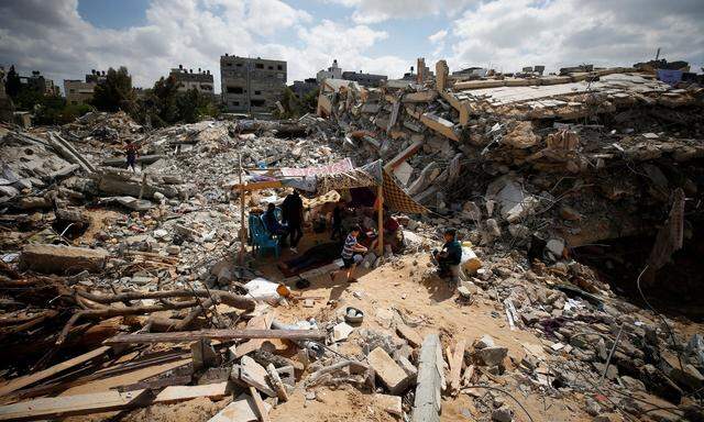 Palästinenser sitzen in einem Zelt auf den Resten ihres zerbombten Hauses.