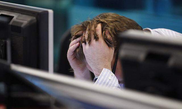 A worker on IG Index´s trading floor holds his head in his hands as markets tumble globally, in London