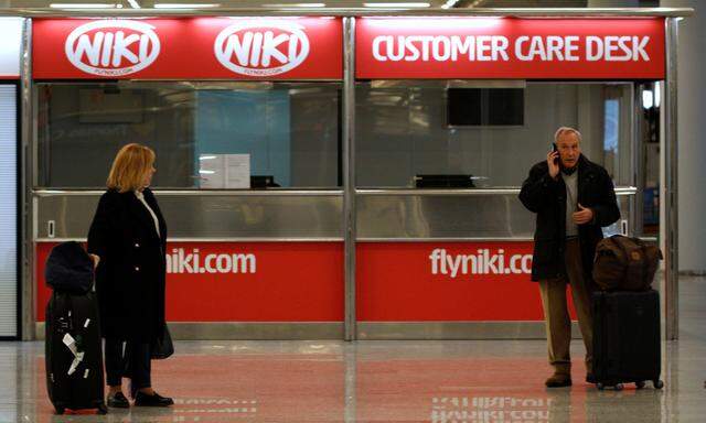 A couple stand near an empty Niki customer care desk at Palma de Mallorca airport
