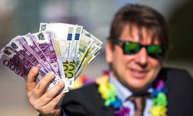 Ein Aktivist hält falsche Banknoten bei einer Demonstration vor der EU-Kommission in Brüssel in die Kamera.