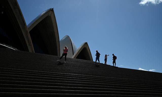 Eine Handvoll Touristen auf den Stufen der verwaisten Oper von Sydney.