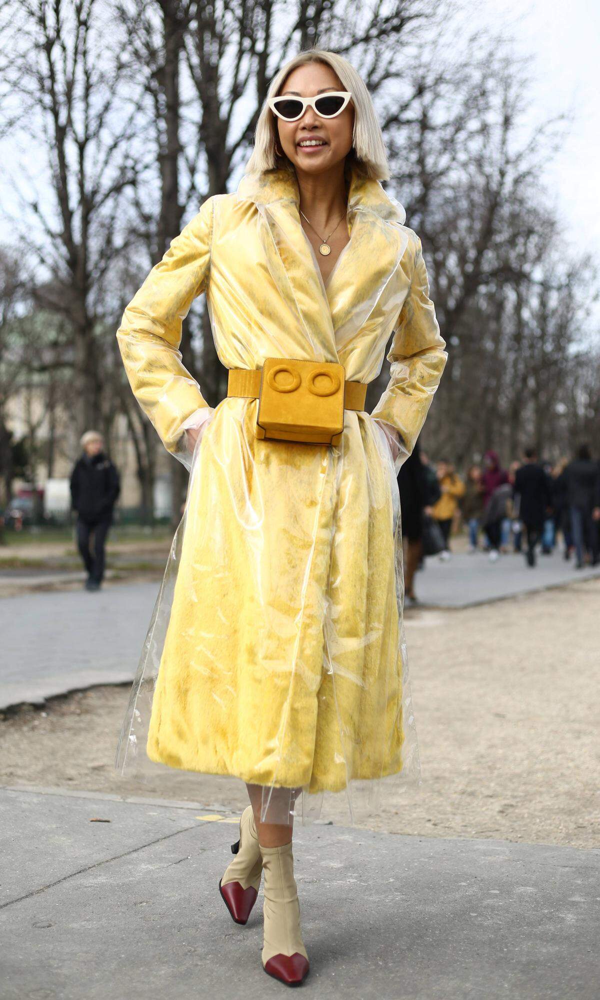 Diese Dame vereint gekonnt mehrere Trends in ihrem Look: Gelb, Plastik, Strumpfboots und das gute Stück um die Taille bringt Form in das Outfit.