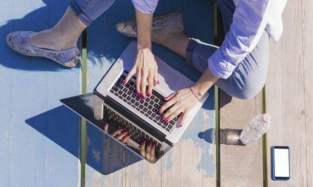 Woman using laptop on wooden boardwalk model released Symbolfoto PUBLICATIONxINxGERxSUIxAUTxHUNxONLY