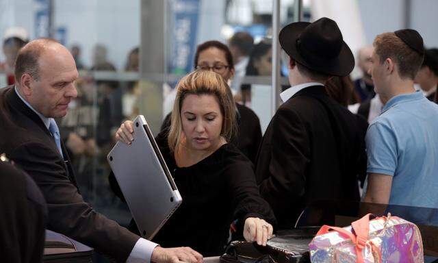 A traveler takes her laptop out of her bag for scanning at Terminal 4 of JFK airport in New York City