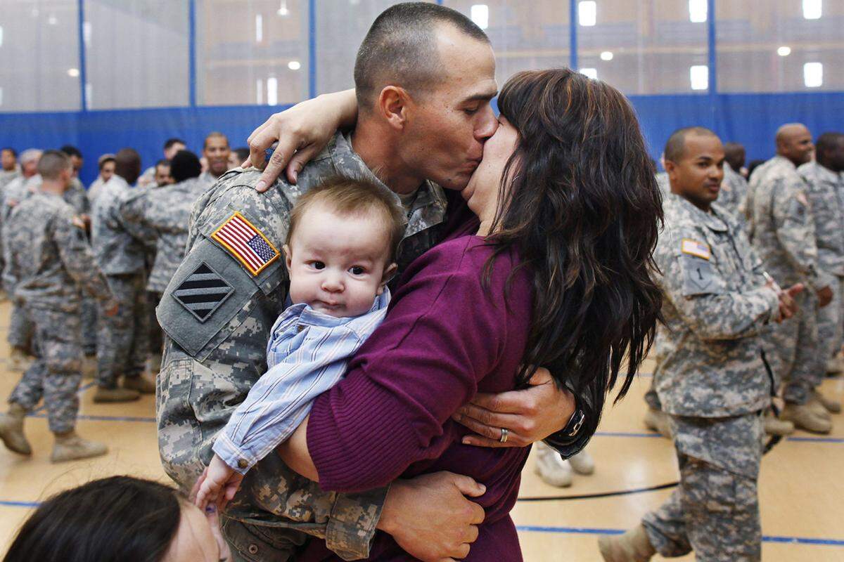 Ein US-Soldat wird von seiner Frau und seinem Kind begrüßt.