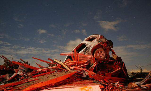 A vehicle sits on a pile of debris from the destruction caused by a tornado in Washington, Illinois