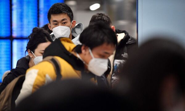 Passagiere aus China kommen am Flughafen in Paris an.