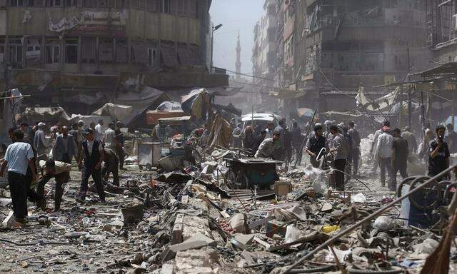 People inspect a site hit by what activists said were air strikes by forces loyal to Syria's President Bashar al-Assad on a marketplace in the Douma neighborhood of Damascus, Syria 