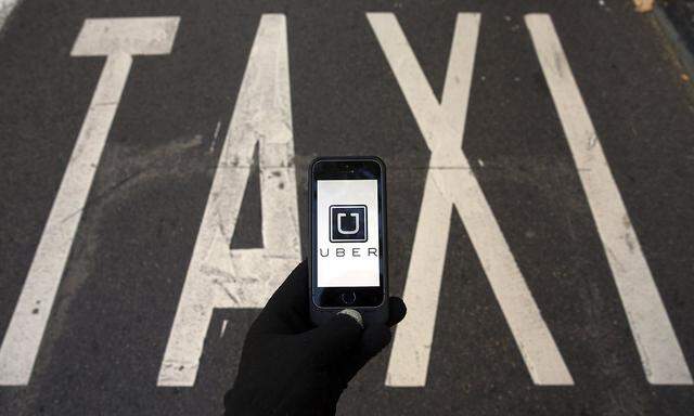 Photo illustration of logo of car-sharing service app Uber on a smartphone over a reserved lane for taxis in a street in Madrid