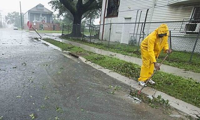 Lloyd Cryer clears debris from gutters in the Lower Ninth Ward as Hurricane Isaac hits New Orleans