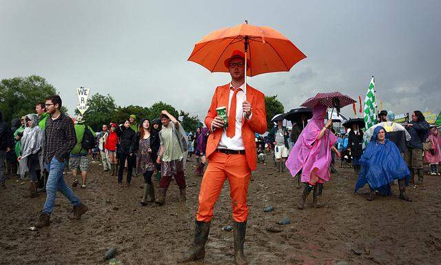 A man dressed in an orange suit watches Robert Plant on the Pyramid stage at Worthy Farm in Somerset, during the Glastonbury Festival
