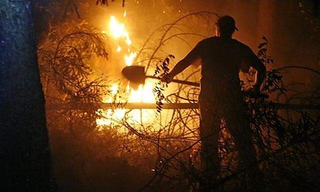 A volunteer from Moscow, who refused to be identified, tries to extinguish forest fire, which came cl