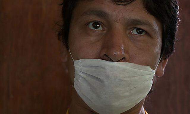 Moises Bonilla, wearing a face mask,  speaks during an interview with The Associated Press at his hom