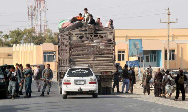 Afghan residents sit on a truck as they leave their home after a battle with the Taliban in Kunduz Province, Afghanistan