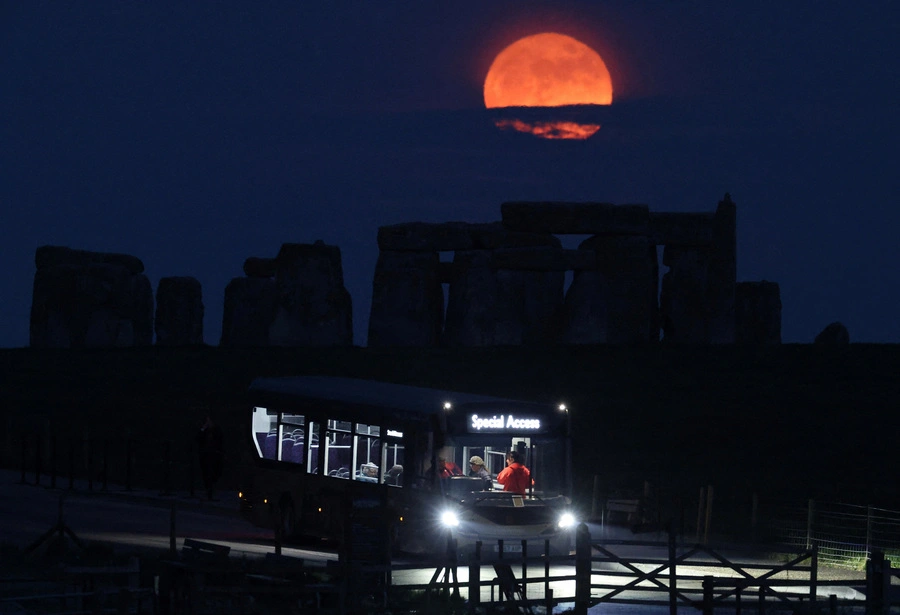 <strong>2. Mai. </strong>Der „Blumenmond“, der Vollmond im Mai, geht hinter der Kultstätte Stonehenge auf, während Besucher in einen Shuttlebus einsteigen.