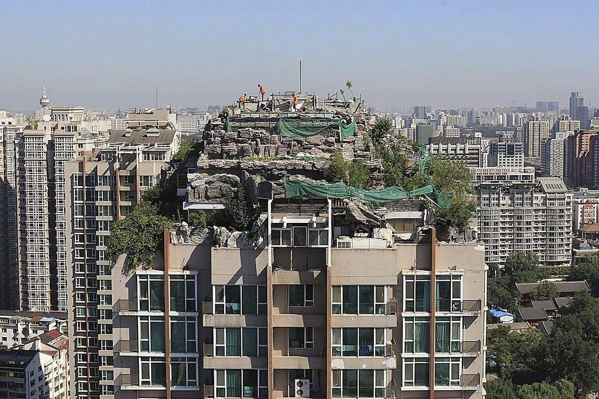 Chinesische Bauarbeiter haben vor kurzem einen Pekinger Wohnturm erklommen, um eine illegal erbaute Felsenvilla abzureißen. Etwa sechs Männer waren auf dem Dach des 26-stöckigen Hauses in der chinesischen Hauptstadt inmitten der Landschaft aus Gestein und Bäumen zu sehen.