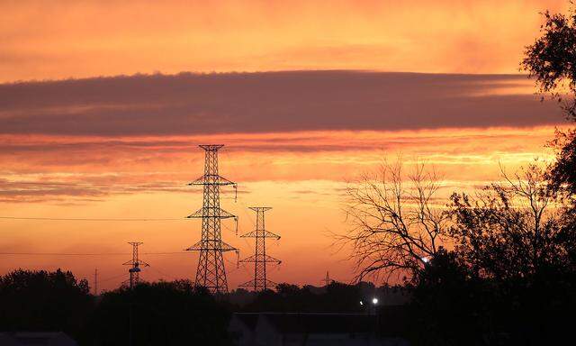 The sun rises behind pylons of high voltage electricity power lines in Halle