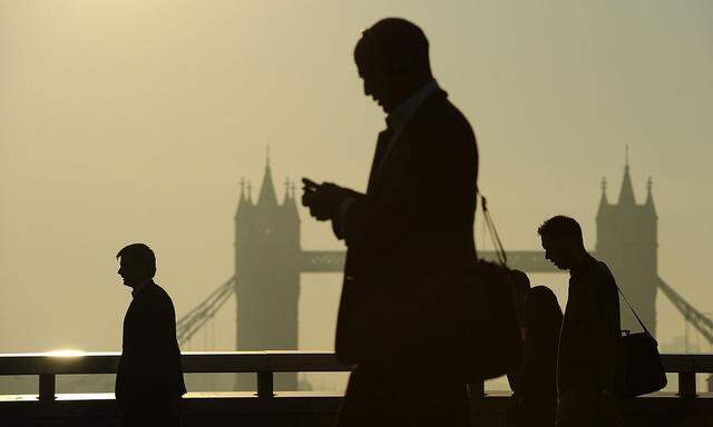 Workers cross London Bridge, with Tower Bridge seen behind, during the morning rush hour in London