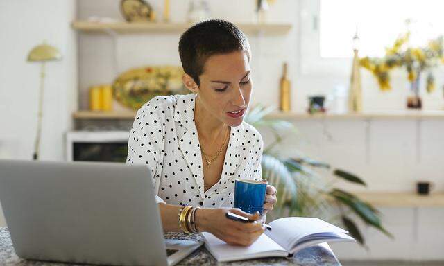 Woman drinking coffee and using laptop and notebook on table model released Symbolfoto property rele