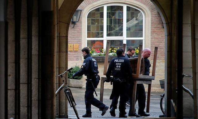 Police carry restaurant table in front of the site where a man drove a van into a group of people sitting outside a popular restaurant in the old city centre of Muenster