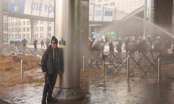 Ein Demonstrant versteckt sich hinter einer Säule vor Wasserwerfern.