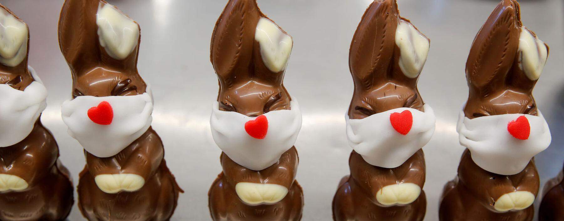 Viele Confiserien - hier Schokohasen aus der Schweiz – statten heuer ihre Osterspezialitäten mit Masken aus.