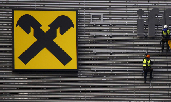 Workers are suspended as they assemble letters of the Raiffeisen Polbank´s bank logo on their new building in Warsaw