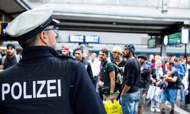 Muenchen Ein Bundespolizist vor einer Gruppe von akommenden Fluechtlingen Copyright Gehrling E