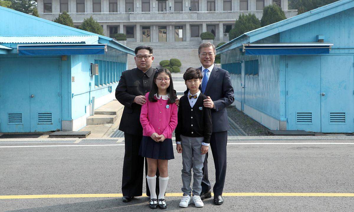 Auch diese beiden südkoreanischen Kinder werden das Treffen wohl nicht mehr vergessen. Nach der ersten Begrüßung posieren beide Staatschefs mit zwei elfjährigen Schülern aus einem nahe gelegenen Dorf. Kim zeigt sich in seinem typischen schwarzen Mao-Anzug, Moon im klassischen Herrenanzug mit blauer Krawatte.
