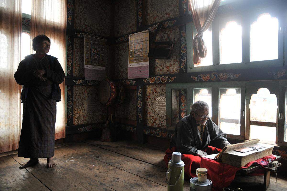 Ein Mönch rezitiert heilige Texte im Haus einer Farmerin im Bezirk Haa. Er kommt ein Mal im Monat um für die Familie des Hauses zu beten.