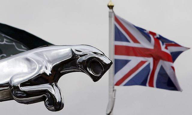 Union flag flies behind Jaguar car emblem outside dealership in Manchester