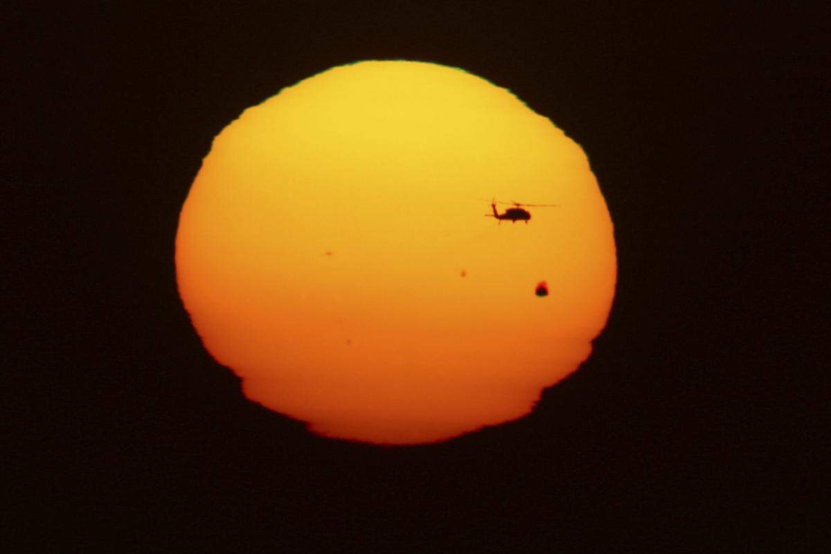 Nur wenn die Venus (Umlaufzeit um die Sonne: 225 Erdentage) die Erde (Umlaufzeit: 365 Tage) ganz nahe an der Schnittlinie der beiden Bahnebenen überholt, kann es zu einem Venusdurchgang kommen. Die Venus ist dabei als kleiner Punkt vor der Sonne zu sehen - perspektivisch kleiner als ein Helikopter, wie diese Aufnahme aus Tijuana (Mexiko) zeigt.