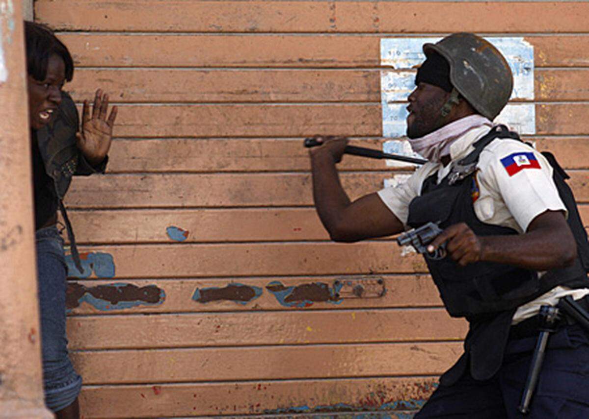 Auch jetzt noch stoßen die Helfer immer wieder auf Probleme. In dieser Woche wurde beispielsweise die Verteilung von Hilfsgütern ausgesetzt, weil gefälschte Lebensmittelcoupons im Umlauf waren. Im Bild: Ein Polizist schlägt am 21. Jänner in Port-au-Prince eine Frau, die im Verdacht steht, an Plünderungen beteiligt gewesen zu sein.