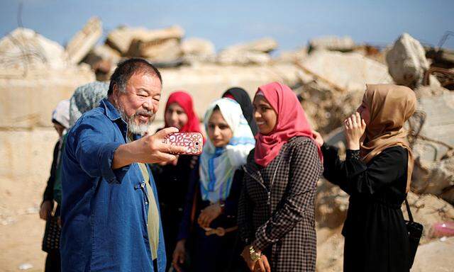 Chinese artist Ai Weiwei (L) takes a selfie with Palestinian girls as he works on a documentary film on refugees, at the Seaport of Gaza City