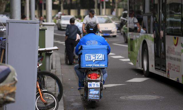 A courier of Ele.me food delivery smartphone application travels on his electric bicycle along a street in Shanghai