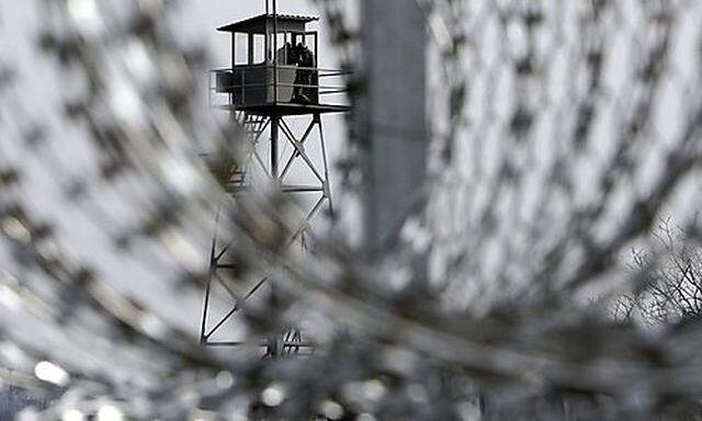 Turkish military watchtower is seen through the barbed wire of a fence, which is being constructed, a