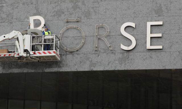 FILE PHOTO: Workers remove the sign 'Boerse' from the former seat of Swiss stock exchange operator SIX Group in Zurich