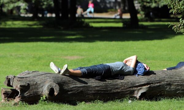sommerliches Herbstwetter in Muenchen Bayern Deutschland Frau genieszt die warme Sonne auf einer Li